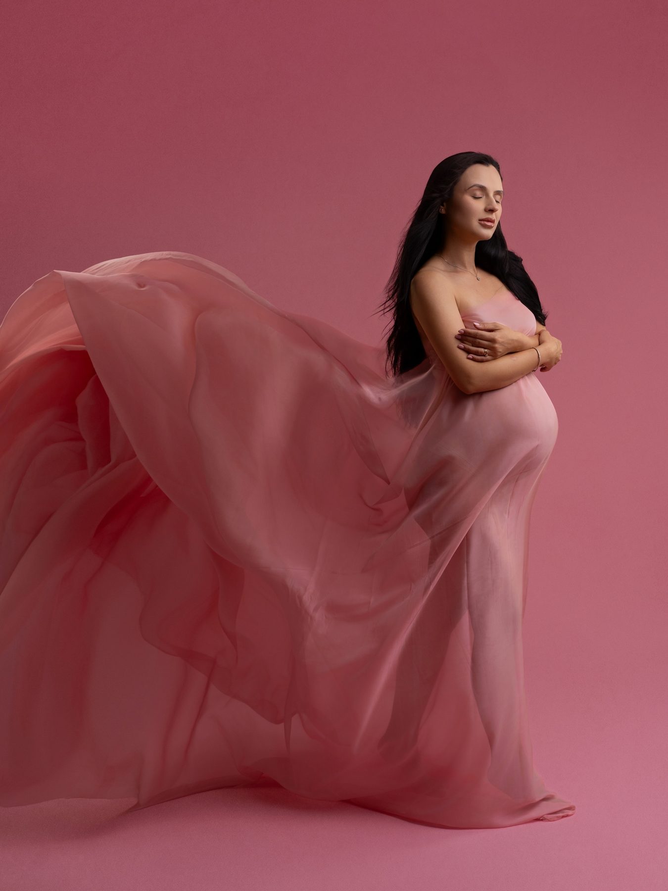 Maternity photograph with a flowing pink veil, in Tina Genovia's studio