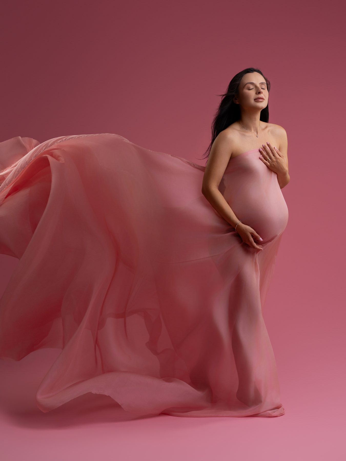 Studio maternity photo session — pink veil in motion on a pink backdrop