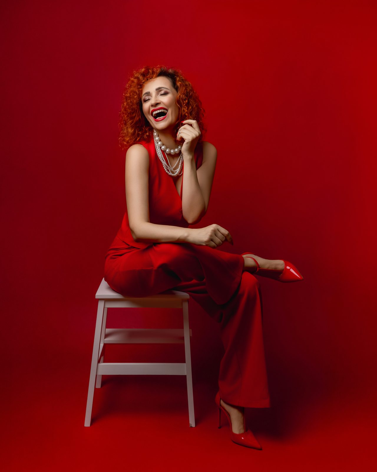 Tina Genovia laughing, dressed in red — portrait in her own studio