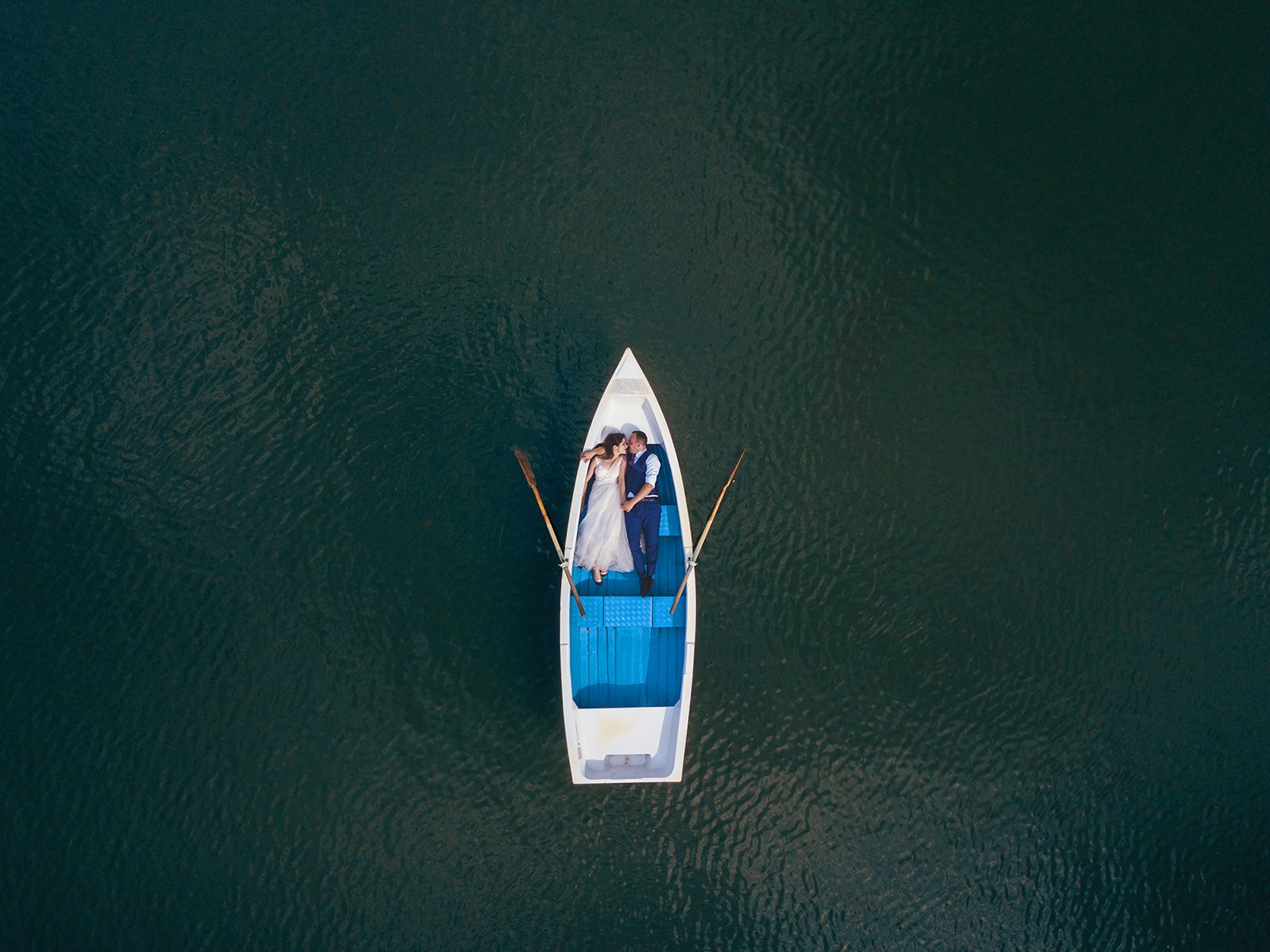 Wedding photo from a drone — newlyweds in a rowing boat on the water
